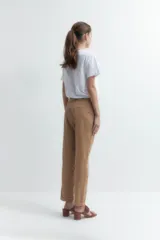 Pantalón de vestir color bordó, de corte recto, con bolsillos laterales y traseros. Se ajusta a la cintura con cinturón de cuero marrón.