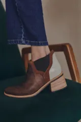 Botineta de diseño tricolor con cuerpo en tono beige, panel elástico lateral negro y talón con textura símil reptil en color marrón. Presenta un taco cuadrado robusto de color negro.