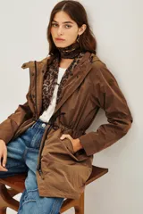 Trench color marrón con capucha, cierre frontal, cordón ajustable en la cintura y bolsillos laterales. Incluye un chaleco interior con estampado animal print.