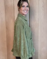 Sobrecamisa de pana color marrón oscuro, con cuello camisero, cierre frontal de botones y detalle de volado en el ruedo. Presenta mangas largas con puños y bolsillos frontales aplicados.