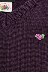 Jersey de punto de algodón color rosado, con cuello en V, manga larga y acabados en rib. Presenta un pequeño parche gráfico bordado en el pecho.
