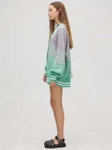 Cardigan de punto con diseño degradé en tonos tierra, patrón de rombos en relieve, cuello en V con cartera de botones y puños con rayas blancas y marrones.