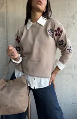 Sweater de punto color beige con cuello redondo y diseño de flores bordadas en tonos oscuros en el frente y las mangas.