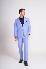 Traje de lino color beige claro, compuesto por saco de dos botones con solapa de muesca, dos bolsillos delanteros con solapa y un bolsillo en el pecho, y pantalón de vestir de corte recto. Incluye camisa blanca, corbata estampada y zapatos marrones.