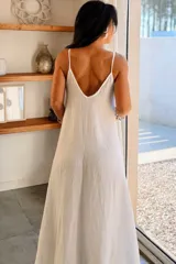 Vestido largo de algodón con diseño amplio, escote en V y breteles finos. La tela presenta una textura sutil con pequeños destellos brillantes.