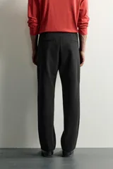 Pantalón negro confeccionado en mezcla de algodón, con cintura elástica, bolsillos frontales y cierre con cremallera y botón.