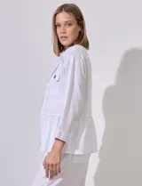 Chaqueta blanca de tencel con cuello con solapa, escote en V y abertura central con broches internos. Tiene corte en la cintura y bolsillos delanteros.