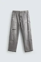 Pantalón de jean estilo carpintero con corte relaxed fit, tiro medio y pierna recta. Presenta un lavado azul medio con efecto desgastado y roturas en las rodillas. Incluye bolsillos laterales tipo plastrón, tira multifunción en la pierna, cierre frontal con cremallera y botón.