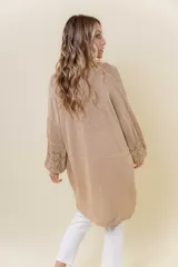 Cardigan tejido liviano color beige con efecto brillante y calados en las mangas. Diseño abierto y corte relajado.