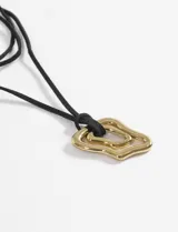 Collar largo con cordón de gamuza marrón y dije de acero quirúrgico con forma irregular y diseño de líneas concéntricas.