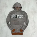 Canguro rústico a rayas horizontales en tonos marrón y gris, con capucha forrada, puños y cintura en color marrón liso. Estampa frontal con la palabra "ICONIC" en letras blancas con borde negro.