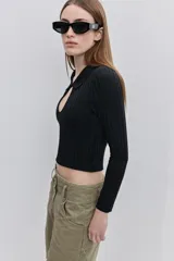 Top de calce al cuerpo color negro, confeccionado en tejido elástico con textura acanalada, con cuello camisero, mangas largas y recorte frontal tipo cut-out.