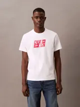 Remera blanca de algodón con cuello redondo y manga corta. Estampado frontal con el logo de Calvin Klein en rojo.