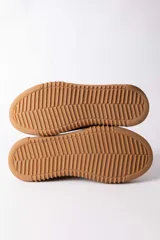Championes urbanos de cuero en color crema con suela de goma gruesa en tono caramelo. Presentan detalles de costuras decorativas en el lateral y un refuerzo en el talón en color gris.