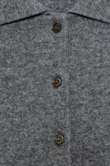Sweater de punto liso color gris melange, con cuello polo, manga larga y cierre frontal con botones. Presenta puños y ruedo acanalados.