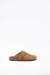 Zueco de cuero vacuno color tostado, con diseño de punta cerrada, ajuste mediante hebilla lateral y suela de corcho con base de goma.