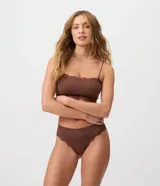 Bombacha de bikini hilo de tiro bajo y laterales medianos, confeccionada en poliamida sin costuras con textura acanalada y detalles de encaje en las aberturas.