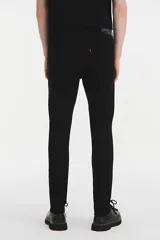 Jean de corte skinny con ajuste estrecho en la pierna, confeccionado en denim elástico color negro. Presenta tiro medio y cierre con bragueta.