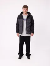 Campera con capucha, diseño bicolor en negro y gris oscuro, con panel frontal acolchado y mangas lisas. Cuenta con cierre frontal, bolsillos laterales y puños elásticos.