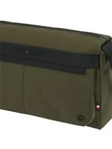 Cartera tipo mensajera de color verde militar confeccionada en nailon con acabado texturizado. Presenta un diseño utilitario con una raya negra a contraste en la parte delantera y el logo metálico de Tommy Hilfiger. Cuenta con un compartimento principal y un bolsillo exterior frontal, ambos con cierre de cremallera, además de una correa ajustable negra.