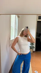 Top sin mangas de color crudo, confeccionado en tela elastizada con textura fruncida y cuello redondo.