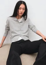 Cardigan gris claro de punto con cierre frontal de botones, cuello redondo y mangas largas.