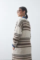 Cardigan largo de tejido de punto con diseño de rayas horizontales en tonos beige, marrón y blanco. Presenta una silueta relajada, mangas largas y frente abierto.