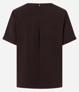 Blusa blanca de poliéster con cuello redondo, mangas cortas, cierre trasero en forma de gota, pequeñas aberturas laterales y acabados en pespuntes en las mangas y el cuello.