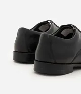 Zapato masculino formal de poliuretano color negro, diseño clásico con cordones y puntera alargada.