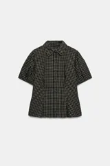 Camisa de cuello solapa y manga corta con pliegues en los hombros. Presenta un diseño de estampado a cuadros y cierre frontal con botones.