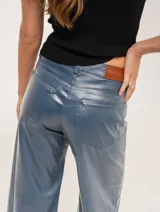 Pantalón de jean elastizado azul con terminación metalizada, corte wide leg, tiro medio, cierre delantero con botón, bolsillos laterales y traseros.