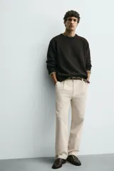 Pantalón relaxed fit color beige confeccionado en tejido de algodón con tacto suave, cintura con pliegues delanteros y cierre frontal con cremallera y botón.