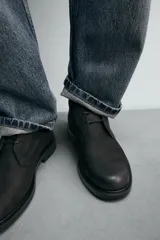 Bota de caña baja con cordones, confeccionada en piel con acabado abatanado. Presenta horma redonda y suela con ligero tacón.