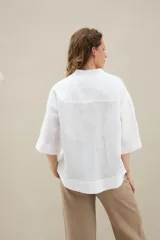 Camisa de lino de calce relajado, color negro, con cuello mao, mangas cortas y bajo redondeado con aberturas laterales.