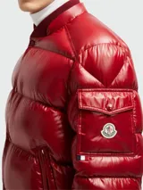Campera puffer Moncler modelo Maljasset, de color rojo brillante, con capucha integrada, cierre frontal con botones a presión, bolsillos laterales con cierre y bolsillo pequeño en la manga con logo de la marca.