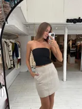 Minifalda de eco cuero color beige con bolsillos delanteros grandes y costuras pespunteadas visibles.