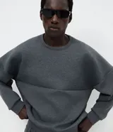 Buzo de cuello redondo y mangas largas con corte oversized. Confeccionado en tejido scuba de estructura firme, presenta un recorte horizontal en el frente que aporta un detalle contemporáneo y minimalista.