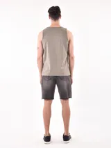 Musculosa sin mangas color verde militar con cuello redondo. Estampado frontal en blanco y negro que simula una fotografía de palmeras en la playa con texto en la parte inferior.