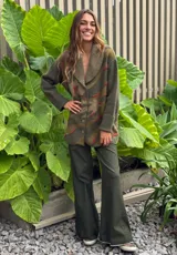 Saco de lana color verde militar con estampado abstracto en tonos verde oliva y detalles bordados en rojo. Tiene cuello solapa, cierre frontal con botones de madera y puños acanalados.