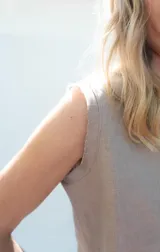 Top de lino sin mangas color salmón, con escote redondo y terminaciones desflecadas en cuello y hombros. Cuenta con cierre trasero de botón de coco.