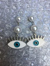 Par de caravanas colgantes con dos perlas blancas y dije de ojo turco con contorno plateado y pupila celeste.