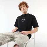 Camiseta negra de cuello redondo y manga corta, con bordado frontal en contraste con la inscripción "NXT-K ORIGINAL STREETWEAR APPAREL".