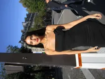 Vestido midi negro ajustado, con tirantes finos, escote recto y detalle de frunce en el lateral del busto. Presenta una abertura lateral en la falda.