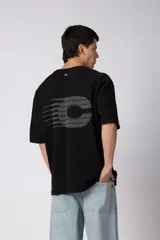 Remerón de corte oversized confeccionado en tejido rústico, con cuello redondo y mangas cortas. Presenta un diseño minimalista con una pequeña estampa frontal centrada en el pecho.