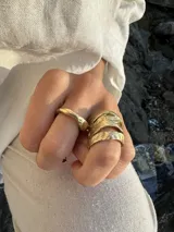 Anillo de diseño enlazado con textura irregular, realizado a mano en bronce. Presenta un diseño abierto que permite regular su tamaño con suavidad.