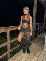 Vestido de red negro con detalles dorados, con top de cuero sintético negro y botas de cuero negras con plataforma.