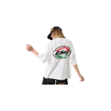 Remera blanca oversize de Eme Studios, con cuello redondo y mangas cortas. Presenta estampados gráficos pequeños en el pecho con inscripciones y logotipos en negro, rojo y verde.