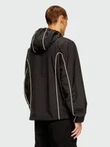 Campera negra con capucha, cierre frontal y ribetes reflectantes en blanco que delinean el cuerpo y los brazos. Presenta un logo bordado en el pecho.