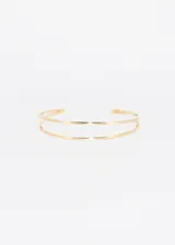 Brazalete abierto dorado de doble línea, ajustable para brazo o muñeca.