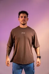 Remera oversize marrón de algodón elastizado con estampado en la espalda que incluye el texto "Crazy Hermod movement" y un diseño de zapatilla alada.